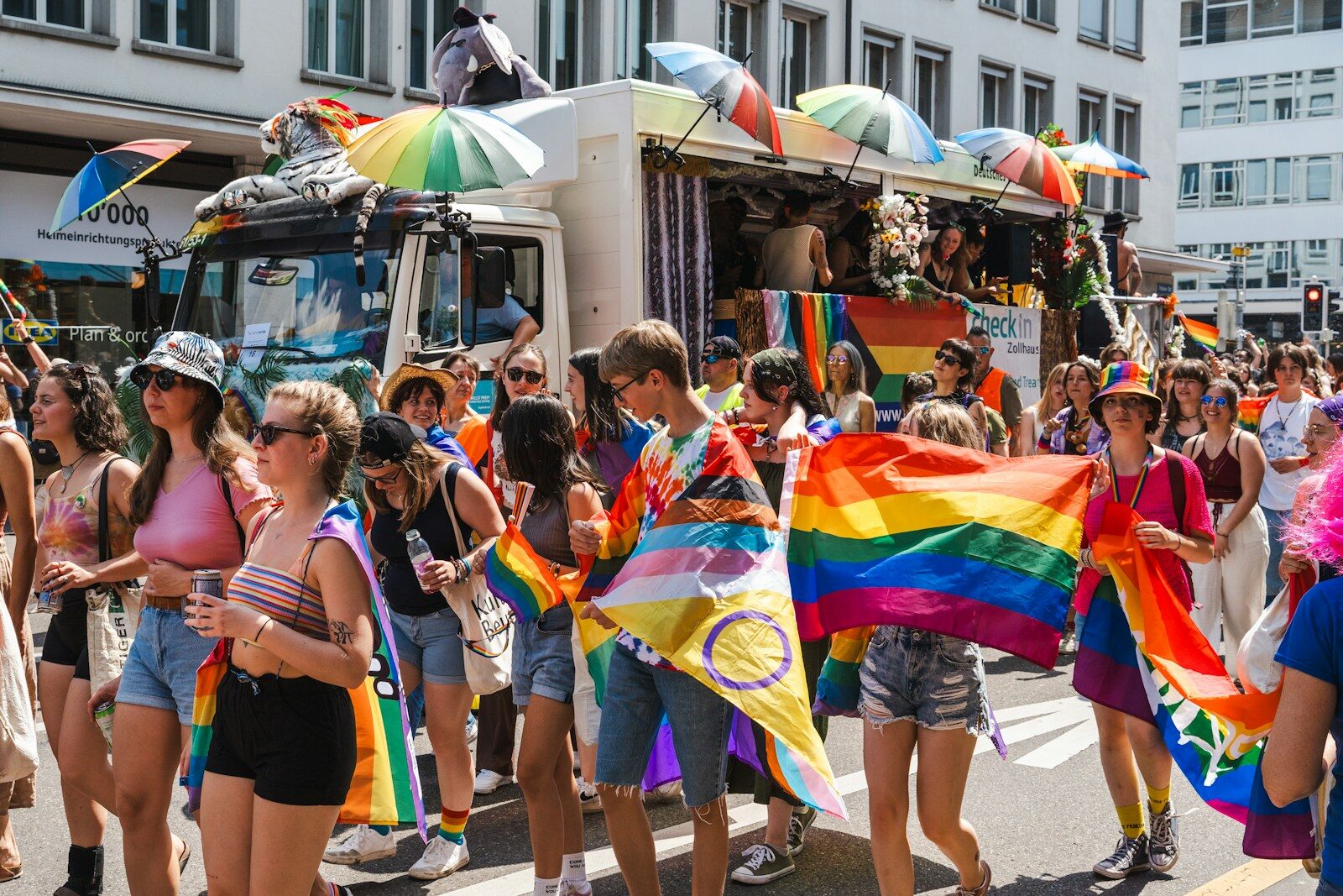 Photo by Ilia Bronskiy a group of people walking down a street holding rainbow flags